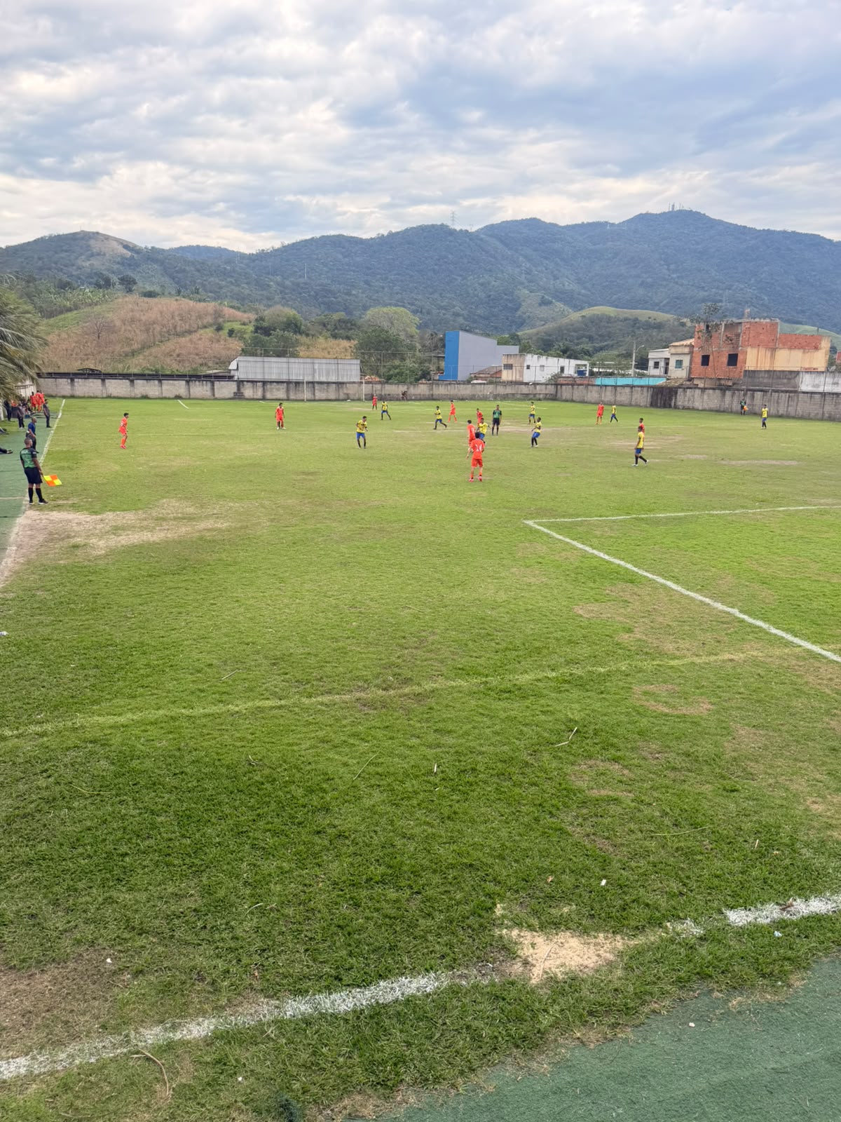 Partida de futebol de base no campo, com montanhas ao fundo